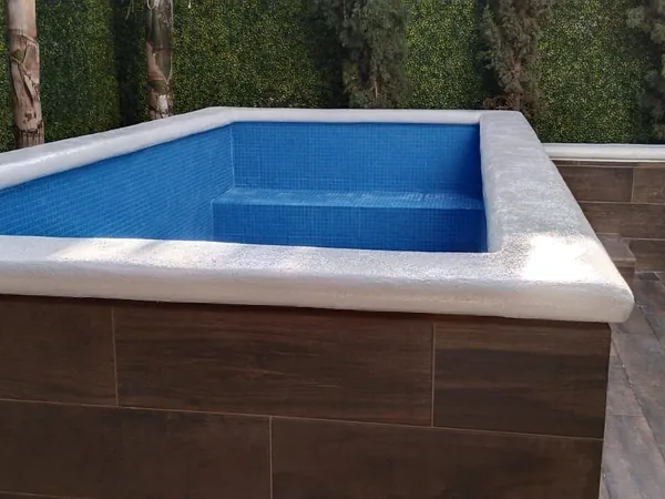 Pileta exterior con enchape tipo madera y sillón en área ajardinada