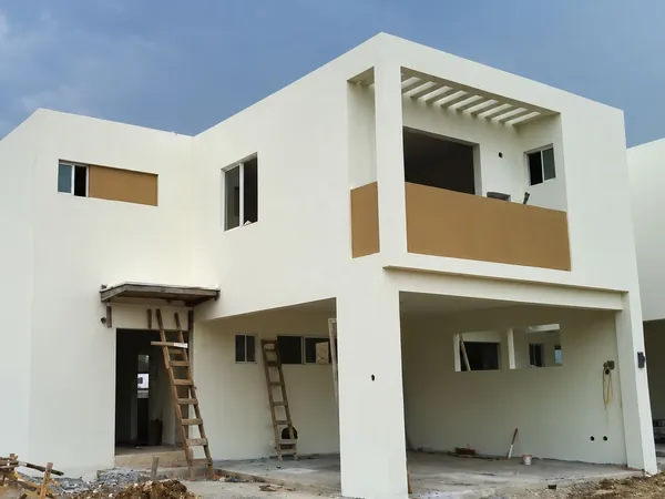 Fachada residencial de dos niveles con acabado exterior blanco y detalle color arena